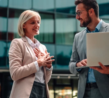 Deux dirigeants échangent avec leur expert-comptable autour d’un ordinateur portable devant leurs bureaux