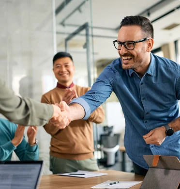 Un créateur d’entreprise serre la main de son conseiller sous les applaudissements de l’équipe